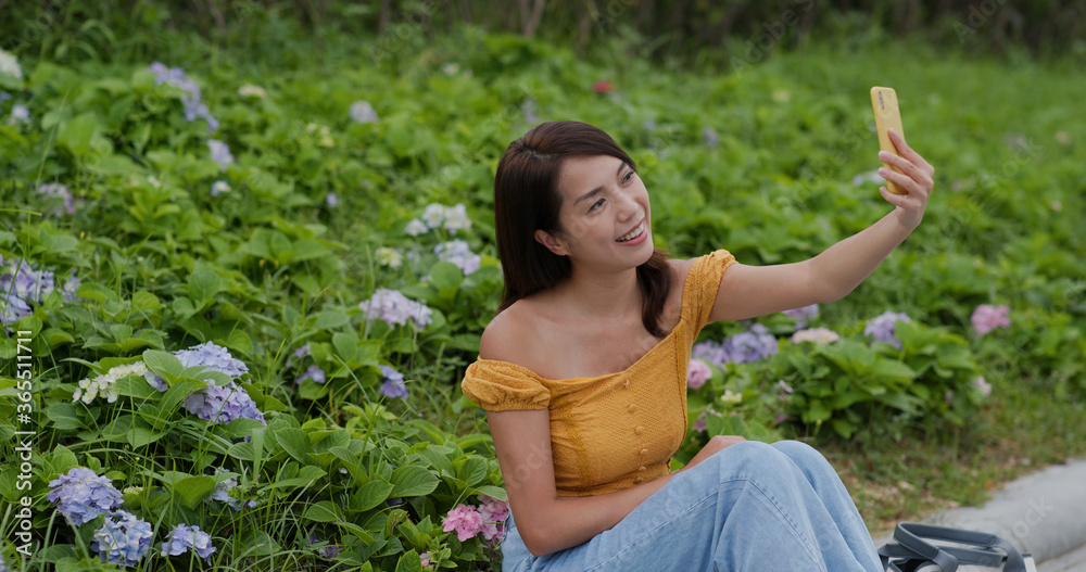 Woman take selfie on cellphone in flower garden Woman take selfie on cellphone in flower garden
