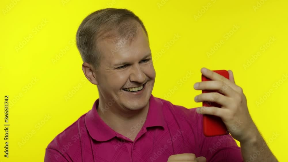 Young man posing in pink t-shirt. Handsome guy using mobile phone, watching funny videos online Young man posing in pink t-shirt. Handsome guy using mobile phone, watching funny videos online