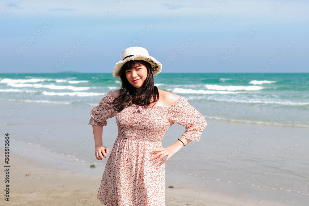 Young Asian woman in a cute dress is relaxing at the beach.