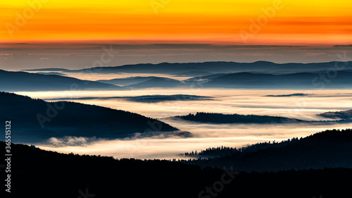 Fototapeta Naklejka Na Ścianę i Meble -  A hazy sunrise in the mountains. Mountains silhouettes and fog in the valleys. Photo from Polonina Wetlinska. Bieszczady National Park. Carpathians. Poland.