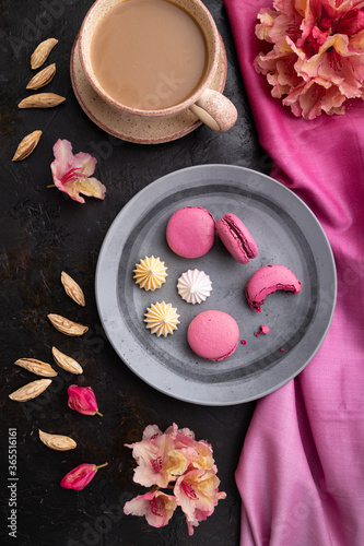 Purple macarons or macaroons cakes with cup of coffee on a black concrete background. Top view, close up