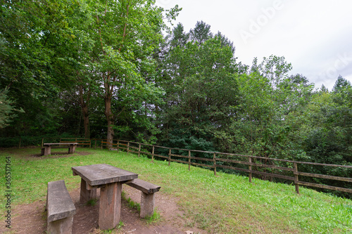 View of picnic area surrounded by a wooden fence, in a forest in northern Spain, horizontal