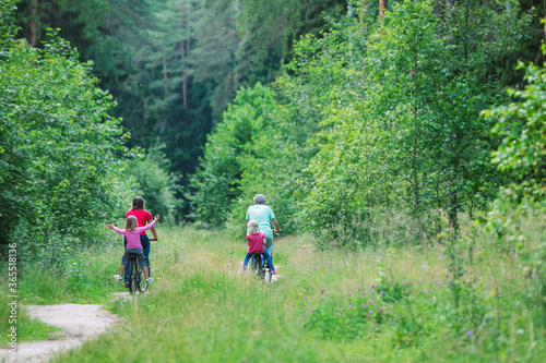 happy active family with kids riding bike in nature