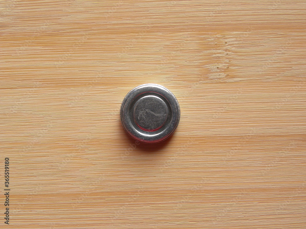Front side of small silver color round internal magnet of over the ear headphone kept on wooden table Front side of small silver color round internal magnet of over the ear headphone kept on wooden table