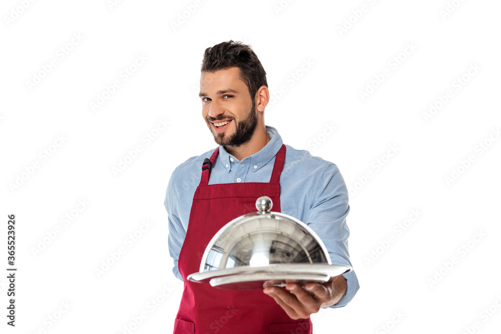 Selective focus of handsome smiling waiter holding tray and dish cover isolated on white Selective focus of handsome smiling waiter holding tray and dish cover isolated on white