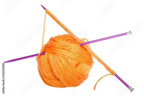 Purple knitting needles with beginning row of work pushed through skein of bright orange yarn forming an X with the needles. Isolated on white.