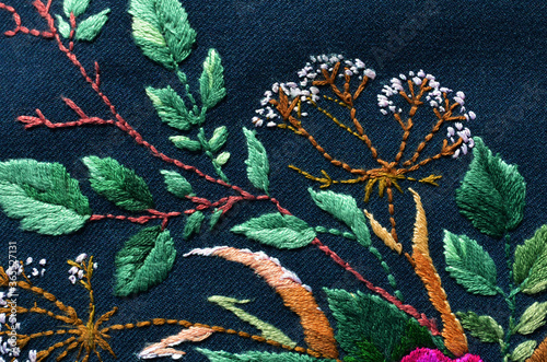 Beautiful pink flowers embroidered on dark fabric. Ukrainian folk embroidery. Fabric decor.