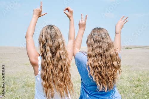 two teenage girls spelling the word love with their fingers