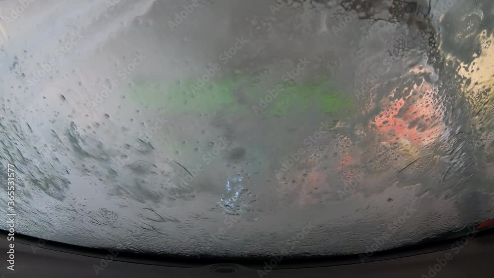 Automatic car wash process in the car wash tunnel. Brushes washing the car windshield. Water