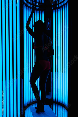 silhouette of a tanned slender girl in a Solarium