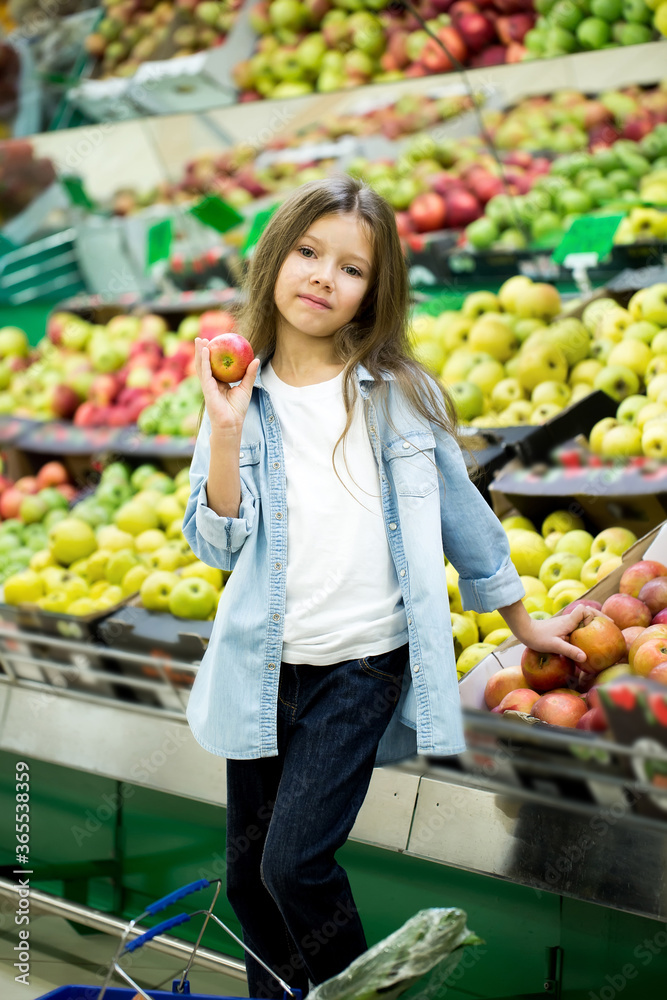 Little girl choosing a bio apple in a store