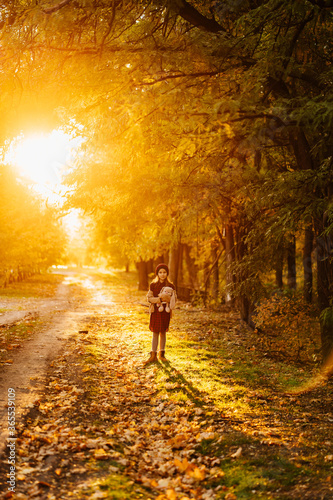 in bright sunlight, girl with hat and plaything is in autumn Park.  © andrey