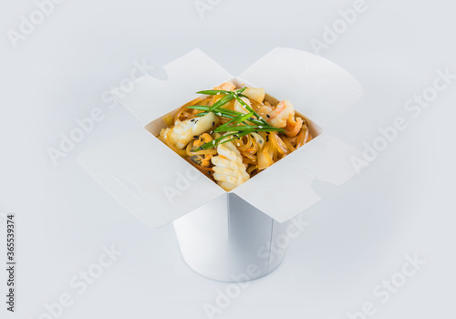 Isolated Food delivery box with ready meals inside. Asian Seafood Harusame rice Noodles with shrimp, mussels, calamari, scallop, vegetables and spring onion scallions in white carton takeaway package
 photo