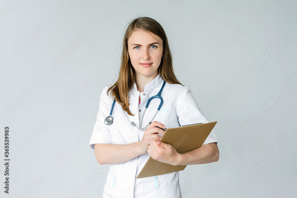 female doctor in a mask and blue phonendoscope writes something in a folder isolated on grey background female doctor in a mask and blue phonendoscope writes something in a folder isolated on grey background