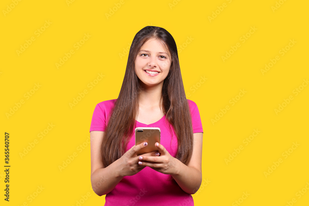 Young beautiful curvaceous woman posing with new phone over isolated background with a lot of copy space for text. Portrait of attractive female with long brunette hair wearing loose pink t-shirt. Young beautiful curvaceous woman posing with new phone over isolated background with a lot of copy space for text. Portrait of attractive female with long brunette hair wearing loose pink t-shirt.