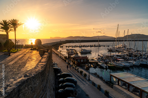 The ancient harbor of Alghero at the sunset with cars, boats and people, on west Sardinia