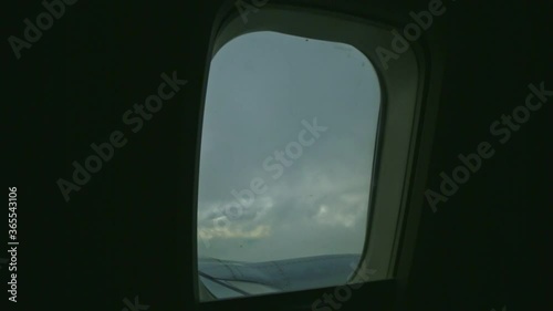 aerial view through airplane window on fluffy white clouds quickly fly above jet engine