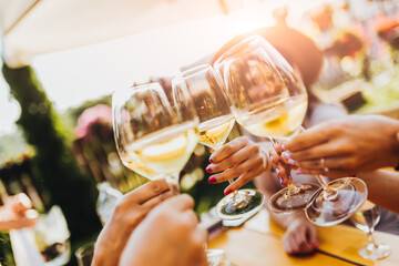 People clinking glasses with wine on the summer terrace of cafe or restaurant