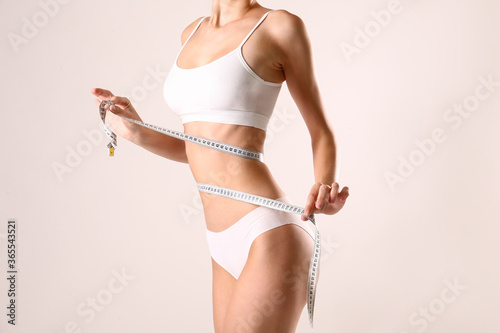 Close up shot of unrecognizable fit woman in lingerie taking measures of her body.