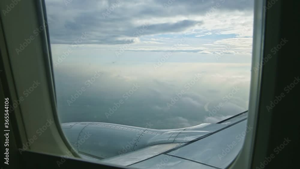 aerial view through airplane window on big steel jet engine fly above fluffy white clouds aerial view through airplane window on big steel jet engine fly above fluffy white clouds