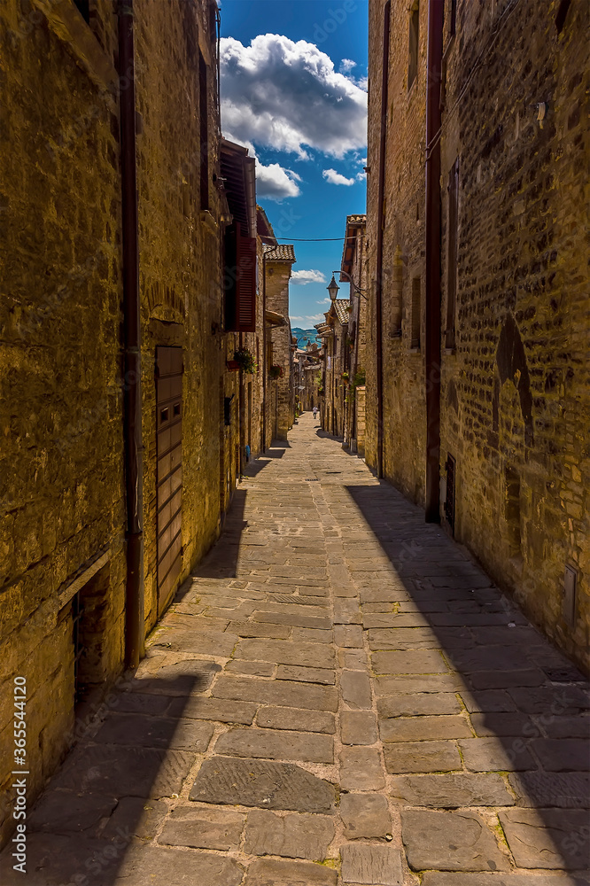 A view down a narrow alleyway at siesta time in the city of Gubbio, Italy in summer