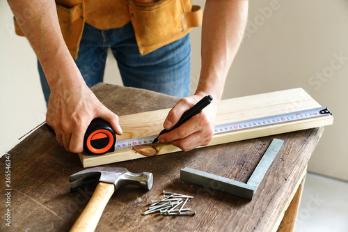 man marks up a board with a tape measure