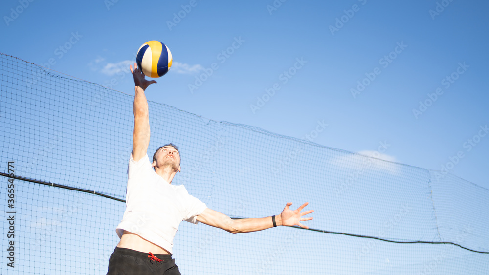 The guy hits the volleyball in the air. Outdoor volleyball game