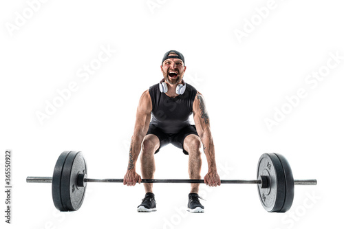 Aggressive bearded strong muscular Man in sportswear and headphones Doing A Deadlift Exercise. Full length studio shot isolated on white.