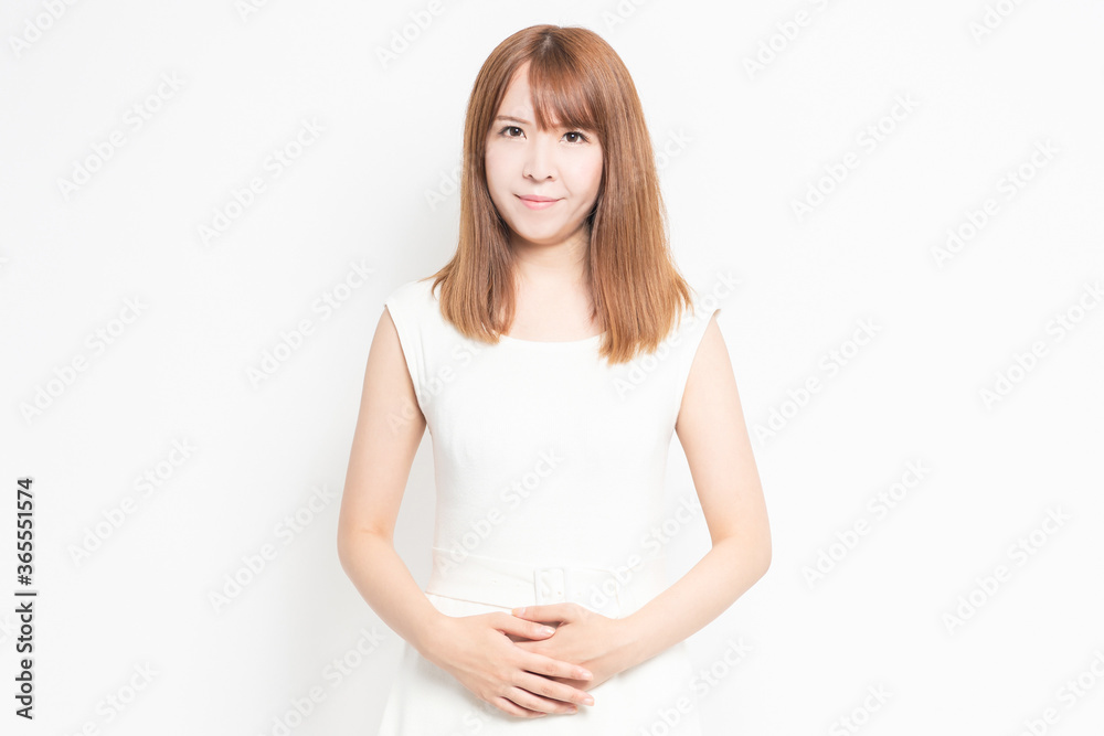 お腹に手を当てる白い服を着た若い女性 お腹に手を当てる白い服を着た若い女性