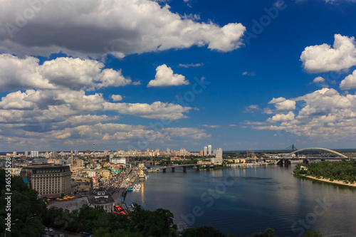 Summer cityscape. Big river in the city under the sky with clouds. The Dnieper River in Kyiv. The historical center of Kyiv.