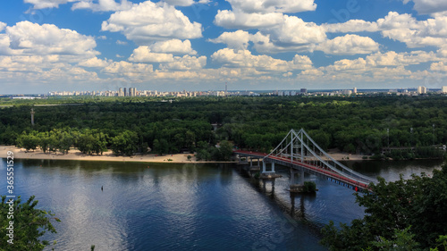 Wallpaper Mural View of the bridge over the river. Sandy beach on the river. Cloudy sky. City summer landscape. Dnipro river in Kyiv on a summer day, Ukraine.  View Of Pedestrian Park Bridge Over The Dnipro River. Torontodigital.ca