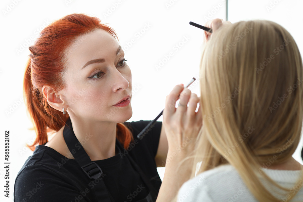 Stylish makeup artist does makeup on face blonde