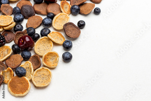 Mini pancakes and berries on white background