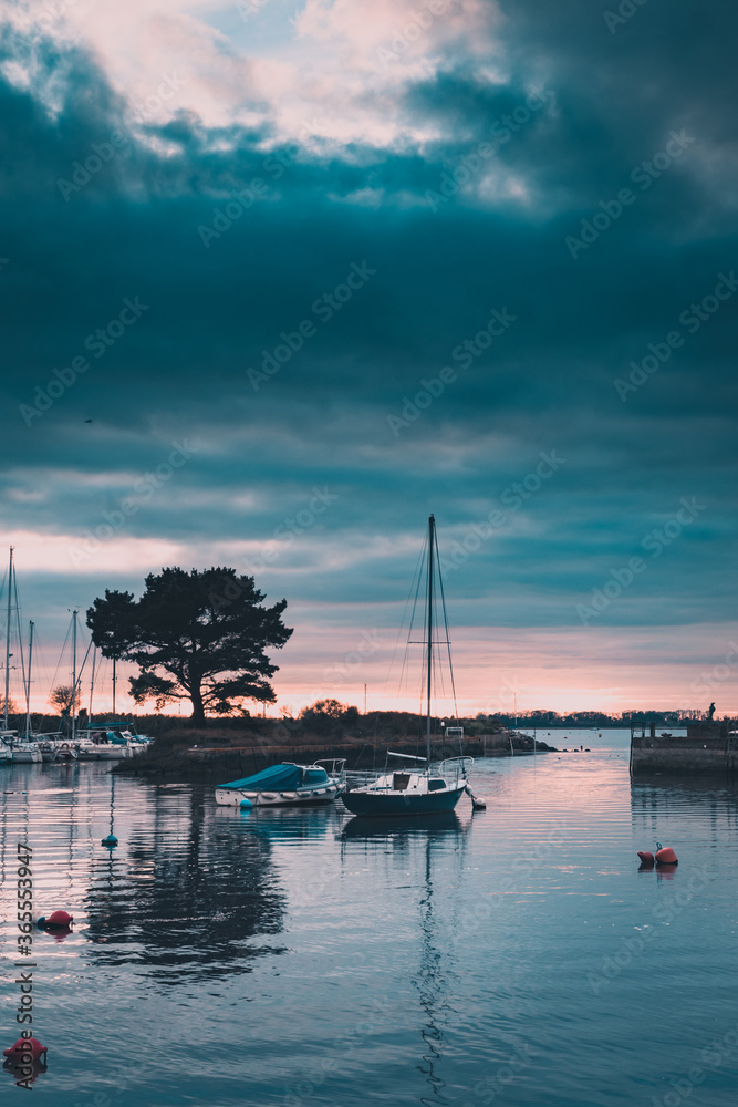 a yacht or sailing boat in a harbour at sunset Emsworth, Hampshire, UK