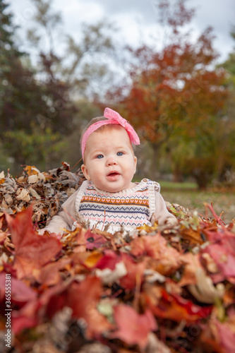 Baby playing outdoors in the fall leaves posing for pictures