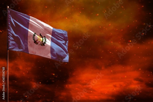Fototapeta Naklejka Na Ścianę i Meble -  Fluttering Guatemala flag mockup with blank space for your text on crimson red sky with smoke pillars background. Troubles concept.