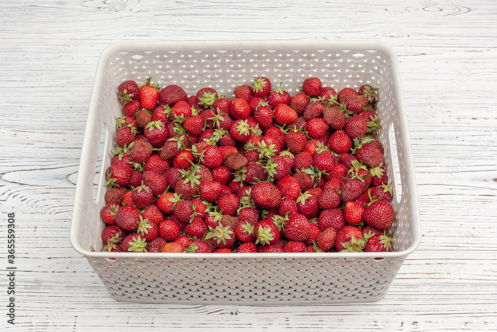 grey plastic box with strawberries on a white painted wooden background grey plastic box with strawberries on a white painted wooden background