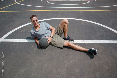 guy in a gray t-shirt and shorts with a dark basketball ball on a basketball court