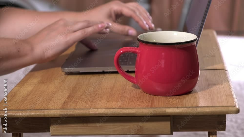 two female hands and a laptop on a wooden bedside table, a girl working at a computer pressing the keys, the concept of remote work at home, freelance two female hands and a laptop on a wooden bedside table, a girl working at a computer pressing the keys, the concept of remote work at home, freelance