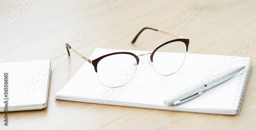 Close-up of glasses with a notebook on the table. Working space