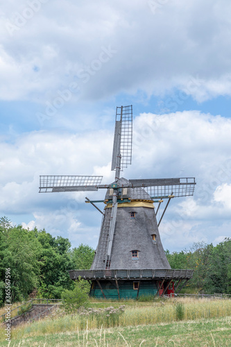 Windmill in rural landscape with blue and cloudy sky