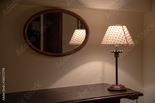 Espejo, mesilla y una lampara encendida en cuarto  photo