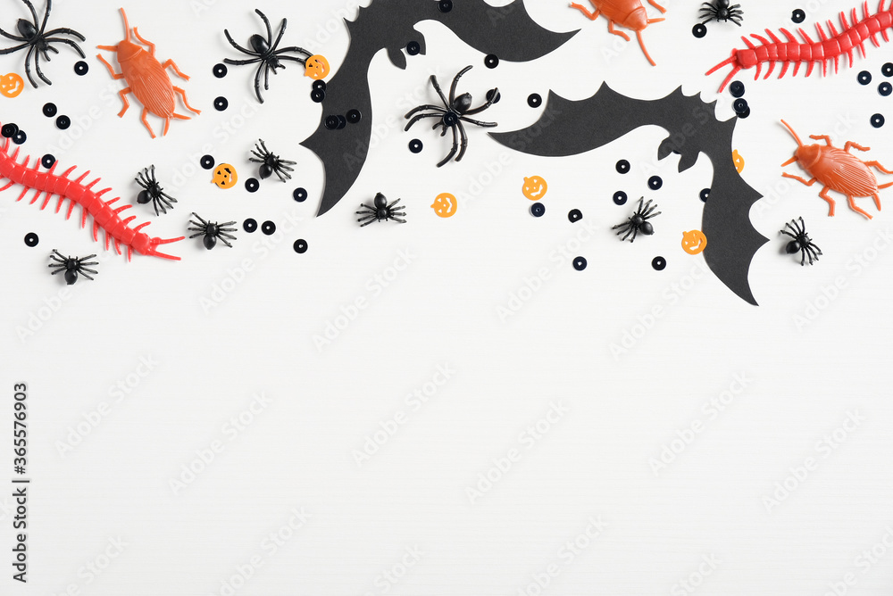 Happy halloween holiday concept. Frame border made of halloween decorations, bats, spiders, insects, confetti on white background. Halloween party greeting card mockup. Top view, copy space. Happy halloween holiday concept. Frame border made of halloween decorations, bats, spiders, insects, confetti on white background. Halloween party greeting card mockup. Top view, copy space.