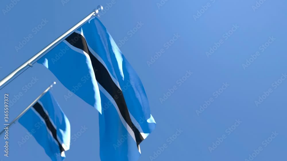 The national flag of Botswana is flying in the wind against a blue sky