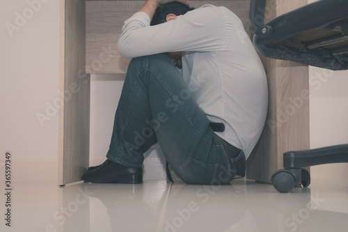 Asian young officer hides under the desk when an earthquake occurs with concept
