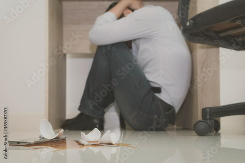 Asian young officer hides under the desk when an earthquake occurs with concept
