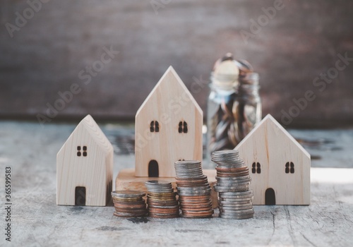 Wood house model money stack of coins on wooden table Background. Savings Plans for Housing. Finance and Banking about concept.