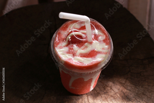 yogurt strawberry smoothie in take away plastic glass on wooden
