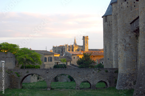 Romantic view of Carcassonne at dusk, Romantic view of Carcassonne at dusk with cloudy sky projecting and orange sunset colours on the medieval city from the castle bridge.