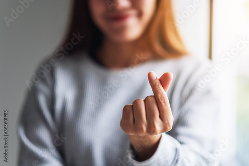 Closeup image of a young woman making and showing mini heart hand sign